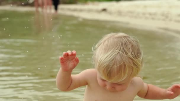 Fotografía en cámara lenta de un bebé jugando con estrellas de mar rojas en una playa — Vídeos de Stock
