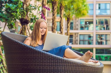 Onun smartphone içinde tarama otelde onu laptop ile havuzun oturan genç kadın serbest meslek sahibi. Bayramlarda meşgul. Uzak iş kavramı. Metniniz için kopya alanı.