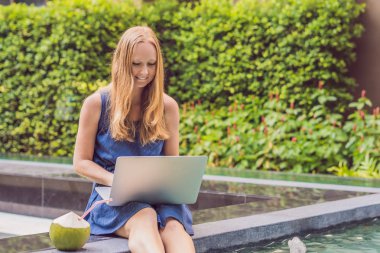 Onun smartphone içinde tarama otelde onu laptop ile havuzun oturan genç kadın serbest meslek sahibi. Bayramlarda meşgul. Uzak iş kavramı. Metniniz için kopya alanı.