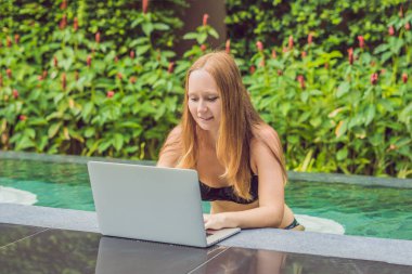 Onun smartphone içinde tarama otelde onu laptop ile havuzun oturan genç kadın serbest meslek sahibi. Bayramlarda meşgul. Uzak iş kavramı. Metniniz için kopya alanı.