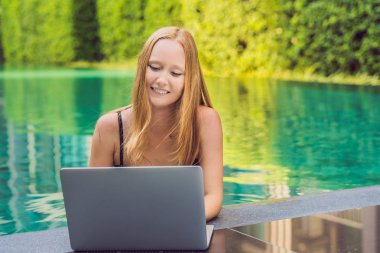 Onun smartphone içinde tarama otelde onu laptop ile havuzun oturan genç kadın serbest meslek sahibi. Bayramlarda meşgul. Uzak iş kavramı. Metniniz için kopya alanı.
