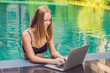 Onun smartphone içinde tarama otelde onu laptop ile havuzun oturan genç kadın serbest meslek sahibi. Bayramlarda meşgul. Uzak iş kavramı. Metniniz için kopya alanı.