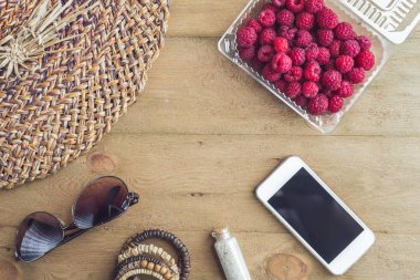 Yaz tatili, tatil, gevşeme kavramı. Ahududu, hasır şapka, cep telefonu, akıllı telefon, kulaklık, güneş gözlüğü. Yaz vibes kavramı.
