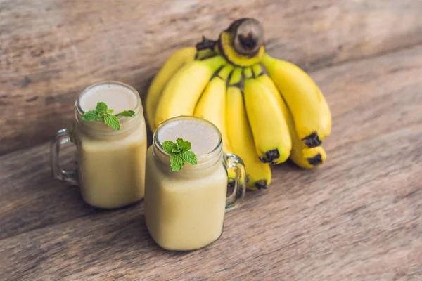 Banana smoothies and bananas on an old wooden background.