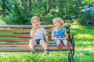 Yeni yürümeye başlayan çocuklar çocuk ve deniz kenarında bir bankta oturan kız ve bir elma yemek.