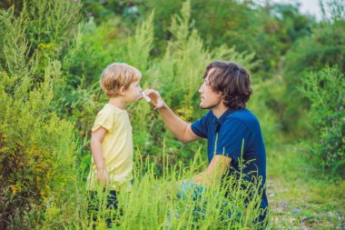 Father and son use a spray from an allergy because of an allergy to ragweed. clipart