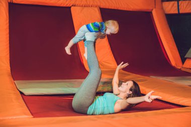 Anne ve oğlu fitness Park'ta bir trambolin üzerinde atlama ve kapalı exersice yapıyor.