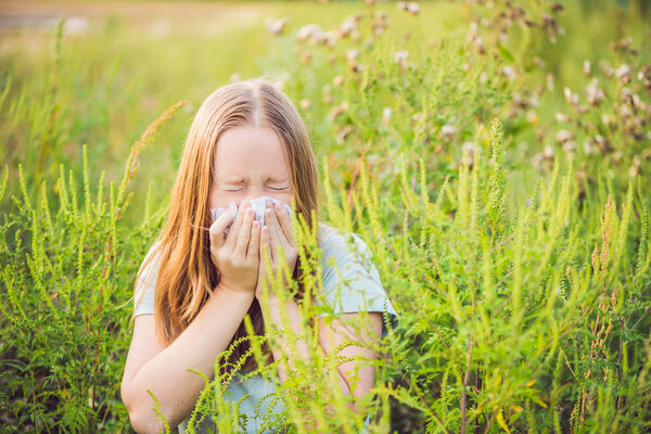 Young woman sneezes because of an allergy to ragweed.