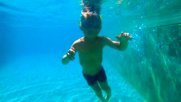 Lentidão ultrahd tiro subaquático de um menino aprende a nadar em uma piscina. Menino de criança mergulha na piscina . — Vídeo de Stock