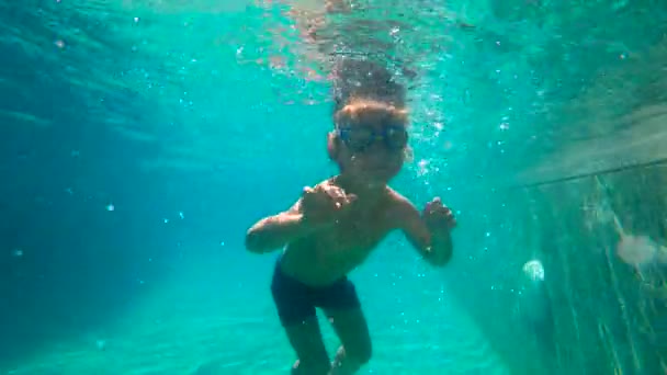 Ralenti ultrahd plan sous-marin d'un petit garçon apprend à nager dans une piscine. Enfant garçon plonge dans la piscine . — Video