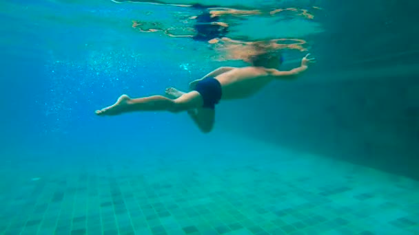 Ultrahd slow motion submarino de un niño aprende a nadar en una piscina. Niño pequeño se zambulle en la piscina y tira de piedras desde el fondo — Vídeos de Stock