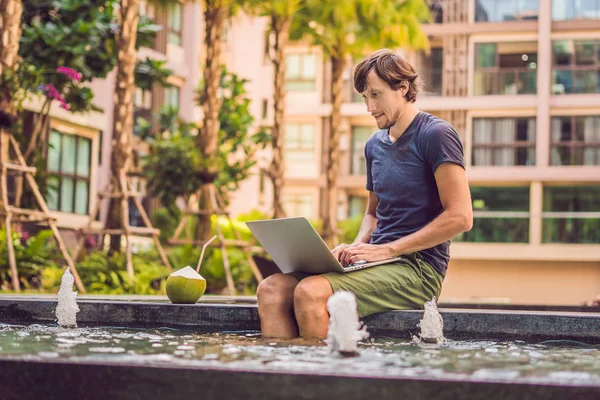 Young freelancer working on vacation next to swimming pool