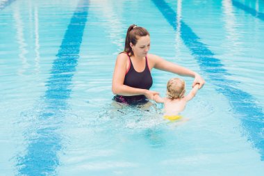 Genç anne küçük oğlu, öğretim gündüz yüzme havuzunda yüzmeyi