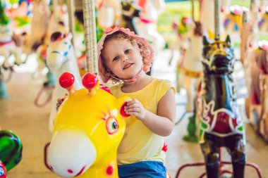 Lunapark içinde zevk ve renkli atlıkarınca şirketten sürme sevimli küçük kız.