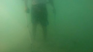 denizin bir metal detektörü takı turistler tarafından kayıp bulmak için kullanma içinde bir adam silüeti