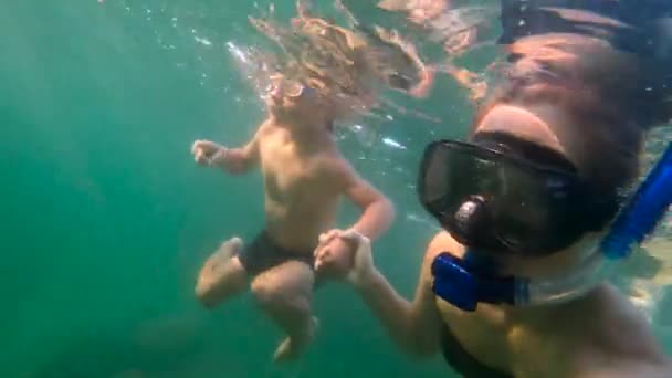 Rallentamento ultrahd colpo subacqueo di una donna e suo figlio sudare e tuffarsi in un mare — Video Stock