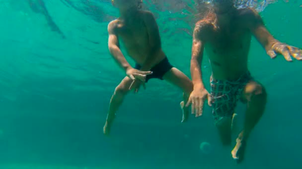 Ultrahd slow motion submarino disparo de un padre enseñando a su hijo a nadar en una piscina. Niño y su padre se sumergen en la piscina — Vídeo de stock