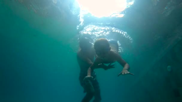 Ultraschallzeitlupe Unterwasseraufnahme eines Vaters, der seinem Sohn das Schwimmen in einem Pool beibringt. Kleinkind und sein Vater tauchen in Pool — Stockvideo