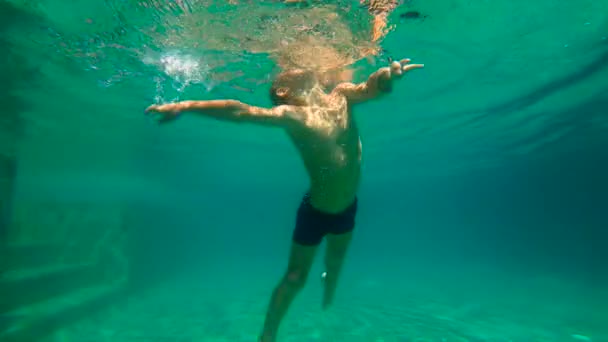 Ультра медленное движение под водой снимок маленького мальчика учится плавать в бассейне. Маленький мальчик ныряет в бассейн . — стоковое видео