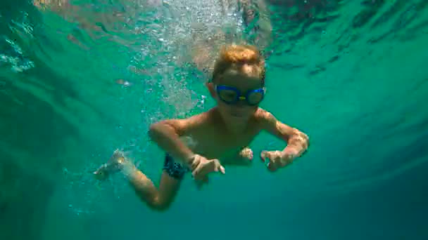 Ralenti ultrahd plan sous-marin d'un petit garçon apprend à nager dans une piscine. Enfant garçon plonge dans la piscine . — Video