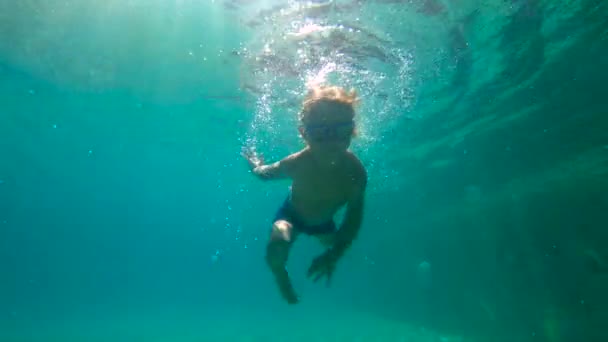 Lentidão ultrahd tiro subaquático de um menino aprende a nadar em uma piscina. Menino de criança mergulha na piscina . — Vídeo de Stock