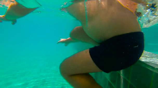 Ultrahd slow motion submarino de un niño aprende a nadar en una piscina. Niño pequeño se zambulle en la piscina y tira de piedras desde el fondo — Vídeo de stock