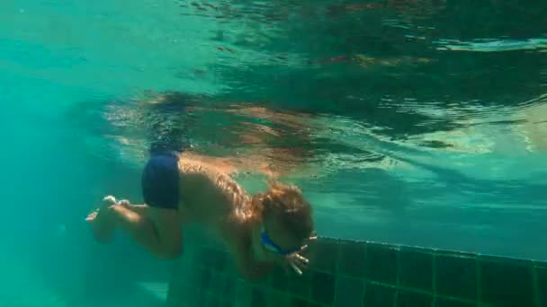 Ultrahd rallentamento colpo subacqueo di un bambino impara a nuotare in una piscina. Bambino ragazzo si tuffa in piscina e tira pietre dal basso — Video Stock