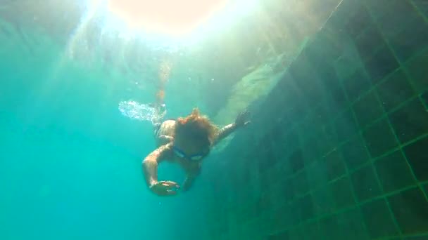 Lentidão ultrahd tiro subaquático de um menino aprende a nadar em uma piscina. Menino mergulha na piscina e puxa pedras do fundo — Vídeo de Stock