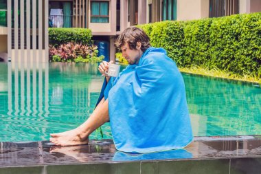 Havuzu üzgün oturan ve çay içme hasta adam