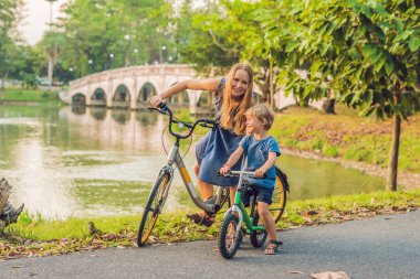 Anne ve açık havada bisiklet sürme ve yakın köprü gülümseyen oğlu