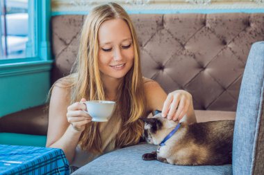 Kahve içme ve kedi okşayarak genç kadın