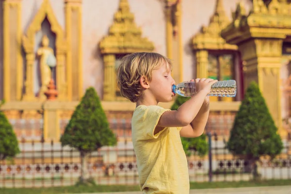 一个旅游男孩在泰国寺庙的背景下在热带地区喝水 — 图库照片
