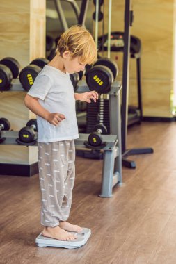 Kilosunu bulmak için ölçekler üzerinde duran genç çocuk