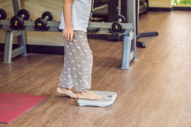 Kilosunu bulmak için ölçekler üzerinde duran genç çocuk