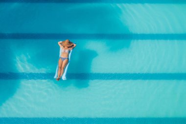 Tatil kavramı. Mavi şişme büyük yüzme havuzunda bikini ince genç kadının Üstten Görünüm.