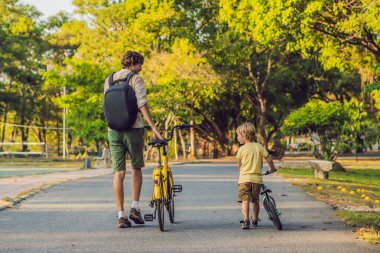Baba ve oğlu açık havada bisiklet sürme ve gülümseyen