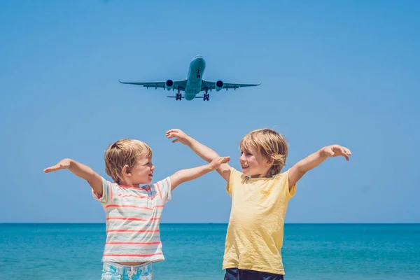 Due ragazzi felici sulla spiaggia e un aereo di atterraggio. Viaggiare con i bambini concetto — Foto Stock