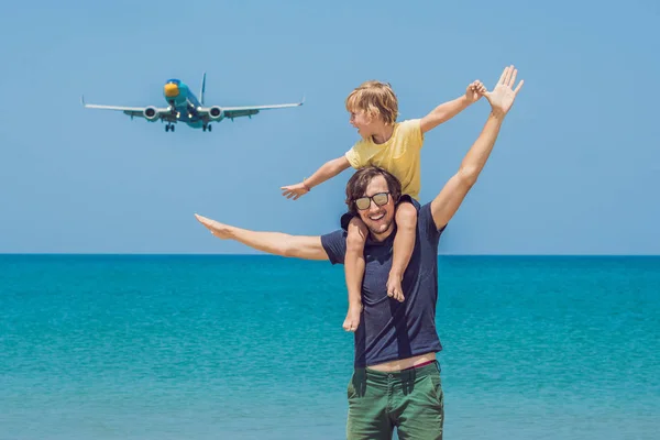 Father and son have fun on the beach watching the landing planes. Traveling on an airplane with children concept Stock Picture