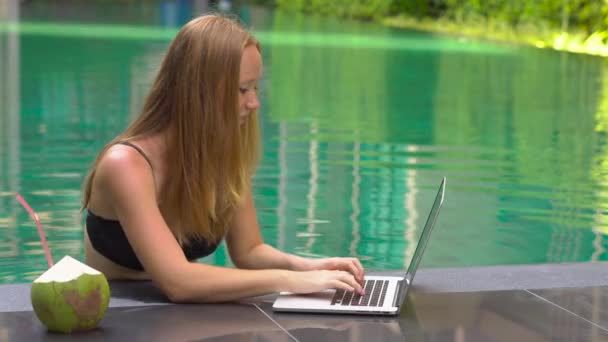 年轻女性自由职业者坐在游泳池附近与她的笔记本电脑 假期很忙 遥远的工作概念 — 图库视频影像