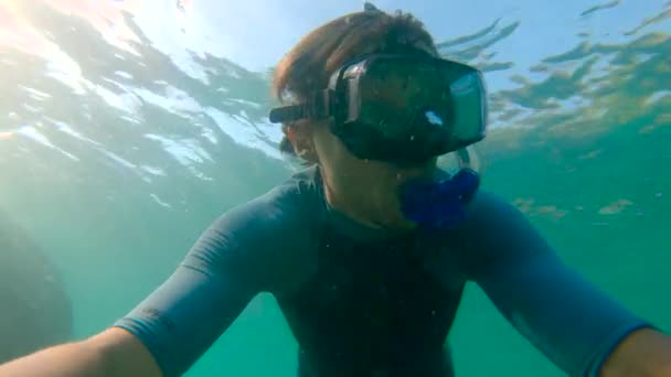 Tikje shot van een jonge man, snorkelen en duiken duik in zee. U.P.F 50 op een mouw van een shirt - geeft ultraviolette bescherming Factor van een shirt. — Stockvideo
