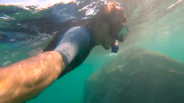 Plan au ralenti d'un jeune homme plongeant en apnée et plongeant dans la mer. U.P.F 50 sur une manche de chemise - indique le facteur de protection ultraviolet d'une chemise . — Video