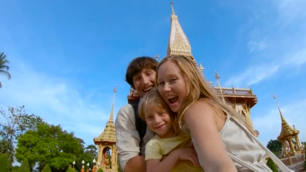 Tikje shot van een fammily doen selfie in fron van een Wat Chalong boeddhistische tempel op Phuket island, Thailand — Stockvideo