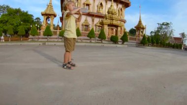 Phuket Island, Tayland tarihinde Wat Chalong Budist tapınağı önünde bir şişe su içme küçük şirin bir çocuk bardak Slowmotion
