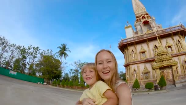 Slowmotion skott av en ung kvinna och hans son gör selfie i fron ett Wat Chalong buddhistiska tempel på ön Phuket, Thailand — Stockvideo