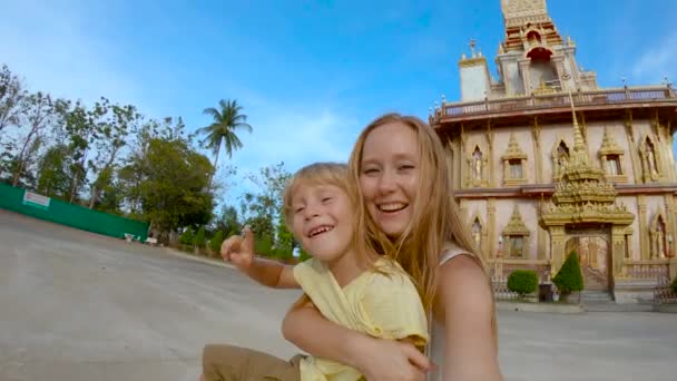 Tikje schot van een jonge vrouw en zijn zoon doen selfie in fron van een Wat Chalong boeddhistische tempel op Phuket island, Thailand — Stockvideo