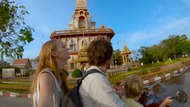 Filmagem em câmera lenta de uma família fazendo selfie andando em uma moto na frente de um templo budista Wat Chalong na ilha de Phuket, Tailândia — Vídeo de Stock