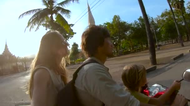 Filmagem em câmera lenta de uma família fazendo selfie andando em uma moto na frente de um templo budista Wat Chalong na ilha de Phuket, Tailândia — Vídeo de Stock