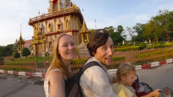 Fotografía en cámara lenta de una familia haciendo selfie en una moto frente a un templo budista de Wat Chalong en la isla de Phuket, Tailandia — Vídeo de stock