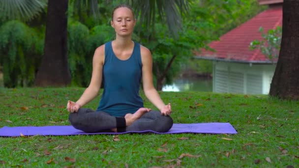 Mujer joven haciendo ejercicios de yoga en un parque tropical — Vídeos de Stock