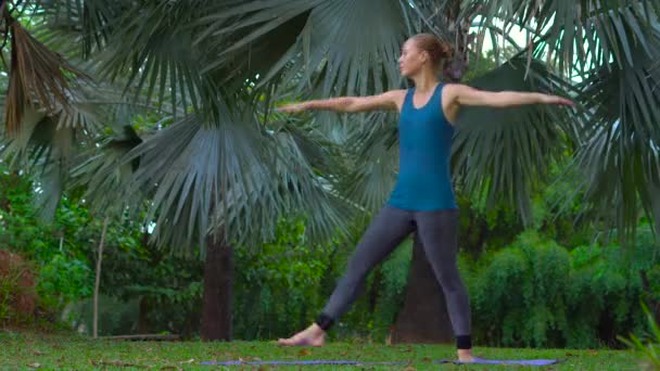 Νεαρή γυναίκα να κάνει ασκήσεις της γιόγκα, σε ένα τροπικό πάρκο — Αρχείο Βίντεο